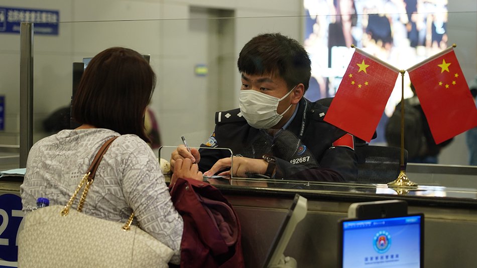 上海机场移民管理警察正在向旅客核实信息