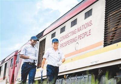 在肯尼亚内罗毕，非洲之星铁路运营公司机辆部的火车驾驶员从一辆蒙内铁路机车旁走过。新华社记者 王冠森摄