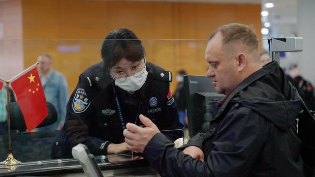 上海机场移民管理警察正向外籍旅客核实信息.