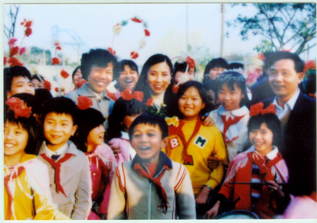 图说：1988年香港区人大、政协代表香港影视明星汪明荃到校视察与六年级学生合影