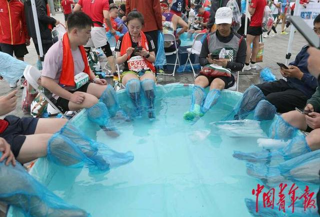 4月14日，北京奥林匹克公园附近，结束比赛后的跑者进行冰水浴足。中青报·中青网记者 陈剑／摄