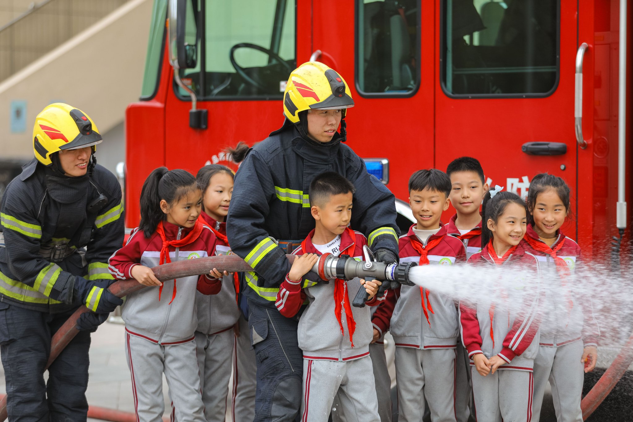 4月15日,在青岛徐水路小学,消防员指导学生使用消防水枪灭火.张鹰 摄