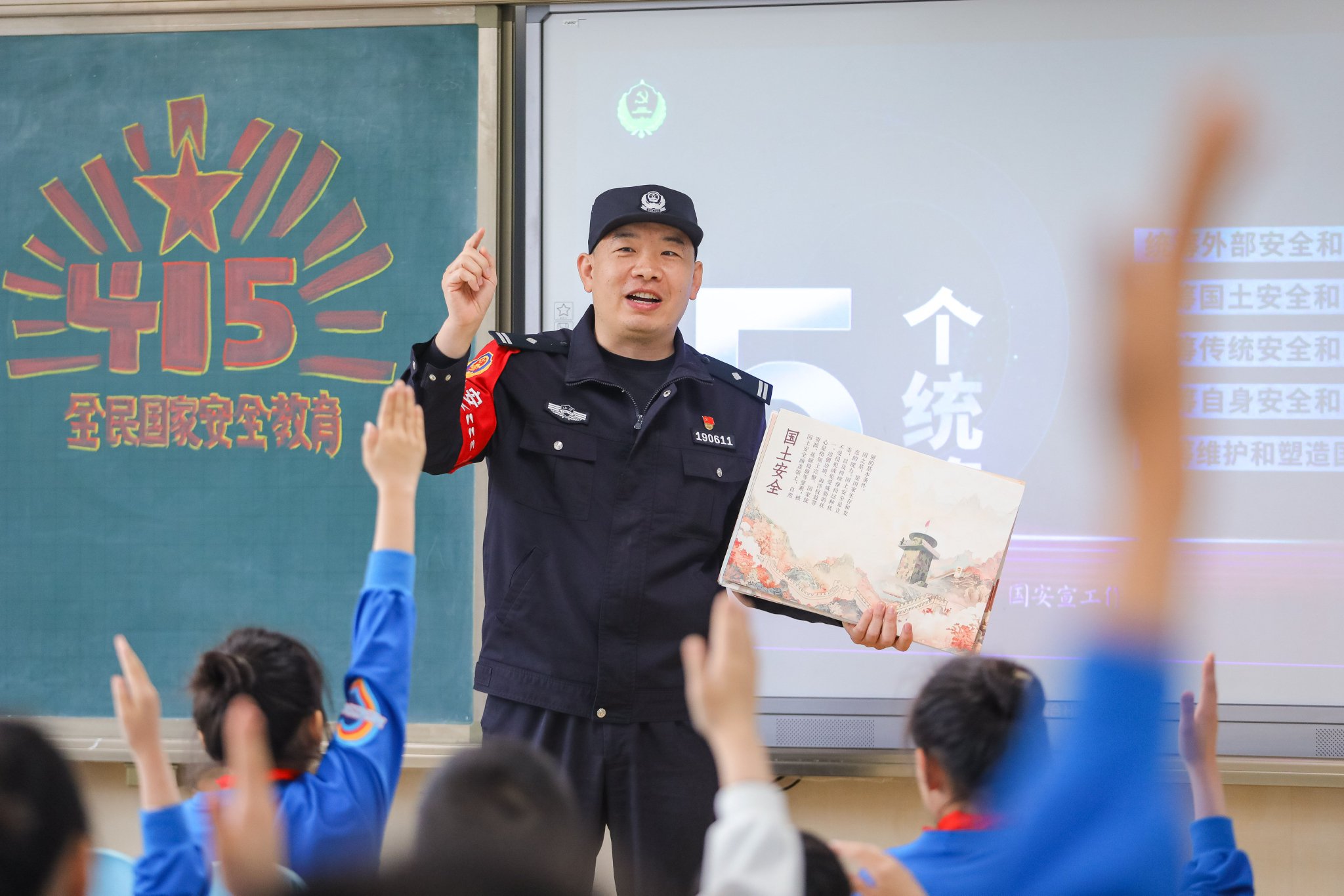 张鹰 摄4月15日,在青岛徐水路小学,消防员为学生讲解灭火防护服的作用