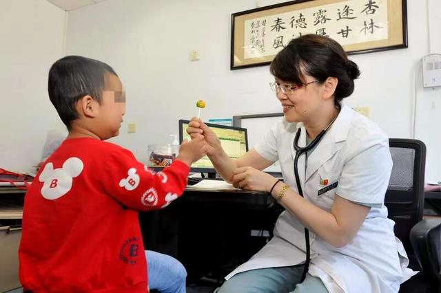 吴润晖医生在诊室里递给血友病患儿糖果。受访者供图