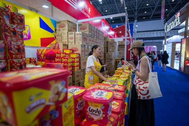 在全球特色消费展区，参观者对来自马来西亚的饼干产生兴趣。人民网记者 翁奇羽摄