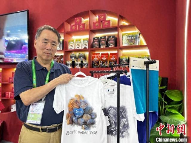 图为台商张建农展示从台湾引进的环保咖啡纱纺织面料制成的海南旅游印花T恤。中新社记者 符宇群 摄