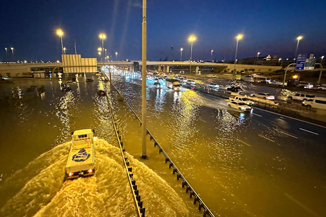 当地时间2024年4月17日，阿联酋迪拜，暴雨过后，车辆行驶在被洪水淹没的街道上。视觉中国 图