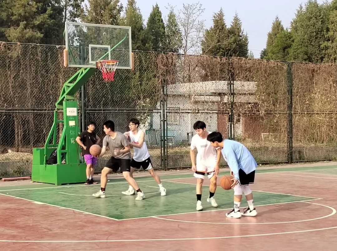 在篮球场，年轻人两两一组，切磋球技。