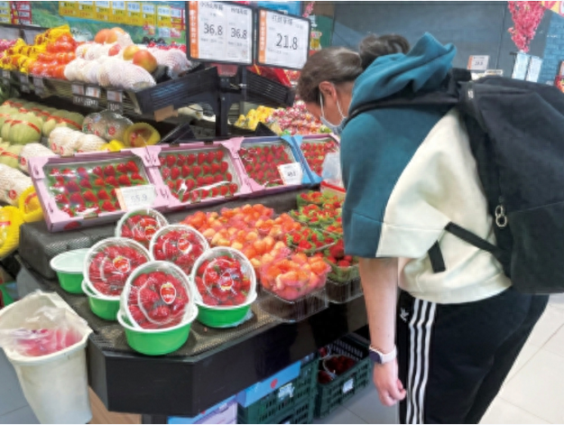 图为消费者在北京某超市挑选购买草莓。