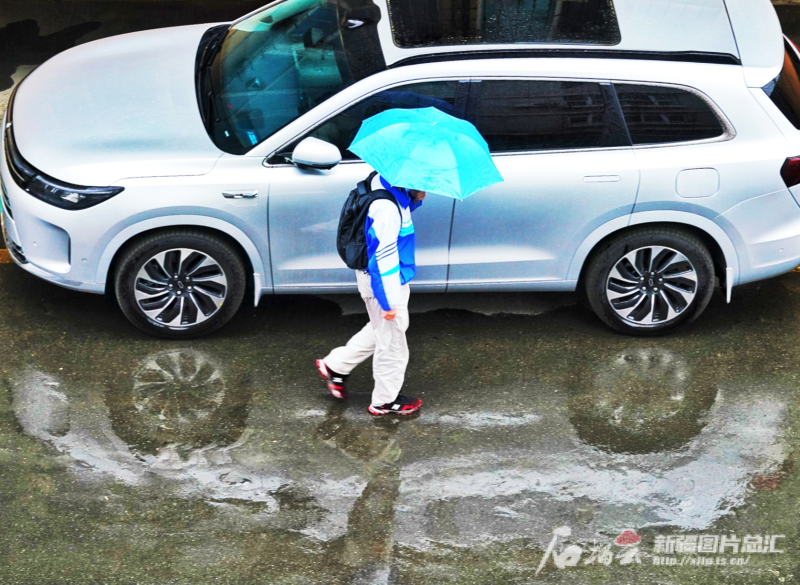4月17日，乌鲁木齐一名学生打着雨伞出行。石榴云/新疆日报记者 张万德摄
