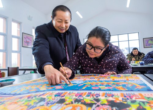 　　图为潘宇在辅导村民学画农民画。