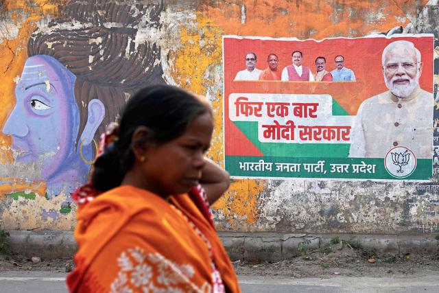 当地时间2024年3月24日，印度瓦拉纳西，在即将举行的大选之前，一名妇女从印度总理莫迪的竞选海报前经过。