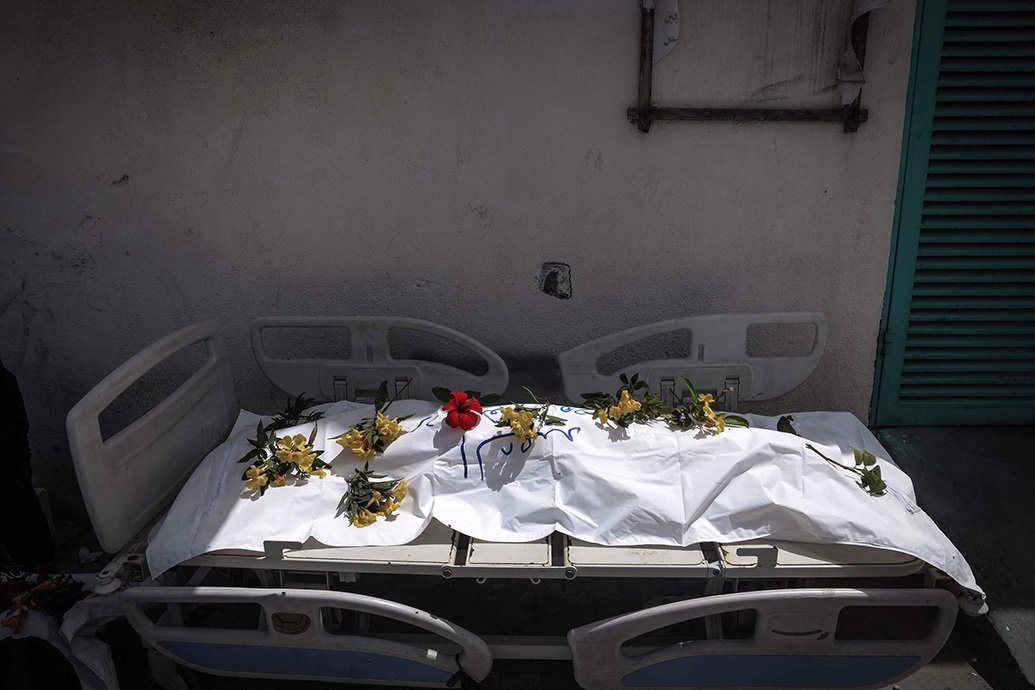 当地时间2024年4月23日，加沙地带南部汗尤尼斯，纳赛尔医院发现的一具尸体被放在病床上，上面覆盖着鲜花，准备安葬。