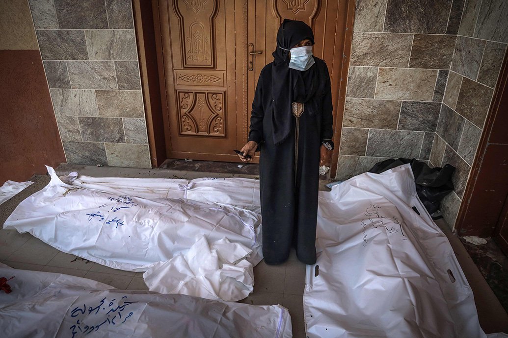 当地时间2024年4月23日，加沙地带南部汗尤尼斯，在纳赛尔医院，一名妇女在不明身份的尸体上做标记。