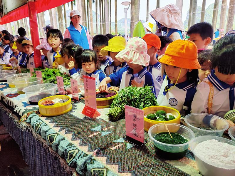 南宁市衡阳东路学校学生在研学活动中观摩糯米饭等传统美食的制作流程。（兰岚 摄）