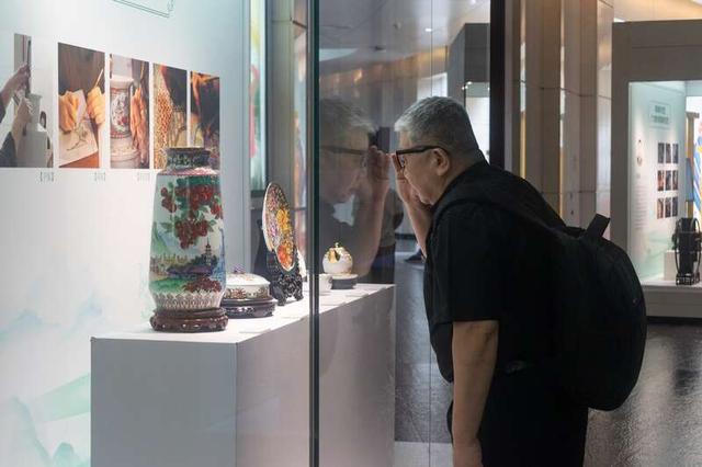 一位参观者在仔细观察广彩作品的细节。陈宇龙/摄