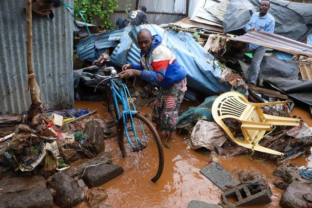 4月24日，在肯尼亚内罗毕马萨雷贫民区，居民在洪水中搬运自行车。新华社发（乔伊·纳布科瓦摄）