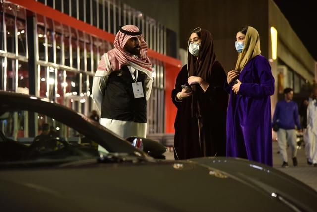 2021年11月24日，在沙特阿拉伯利雅得2021国际车展现场，两名女子与汽车销售人员交谈。新华社记者王海洲摄
