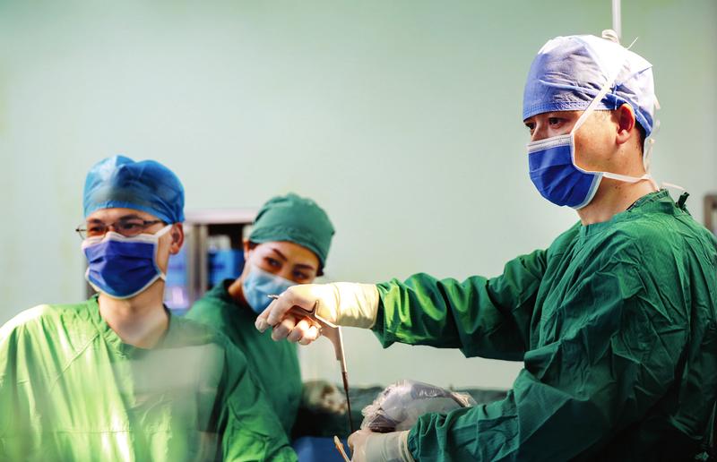 南宁市第二人民医院外科第二党支部书记刘剑伟（右）带领脊柱外科团队为患者实施手术帮助患者恢复健康。（陈永尚 摄）