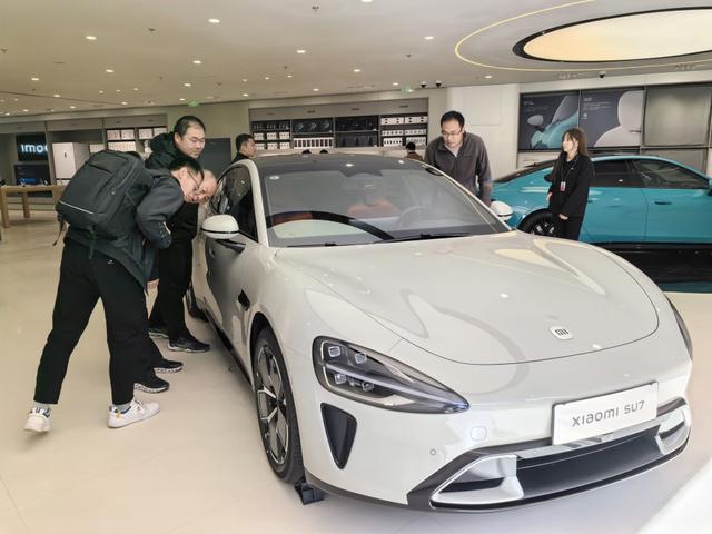 ↑在北京一家小米汽车零售门店内，消费者在了解小米新能源汽车SU7（3月28日摄）。新华社记者鞠焕宗 摄