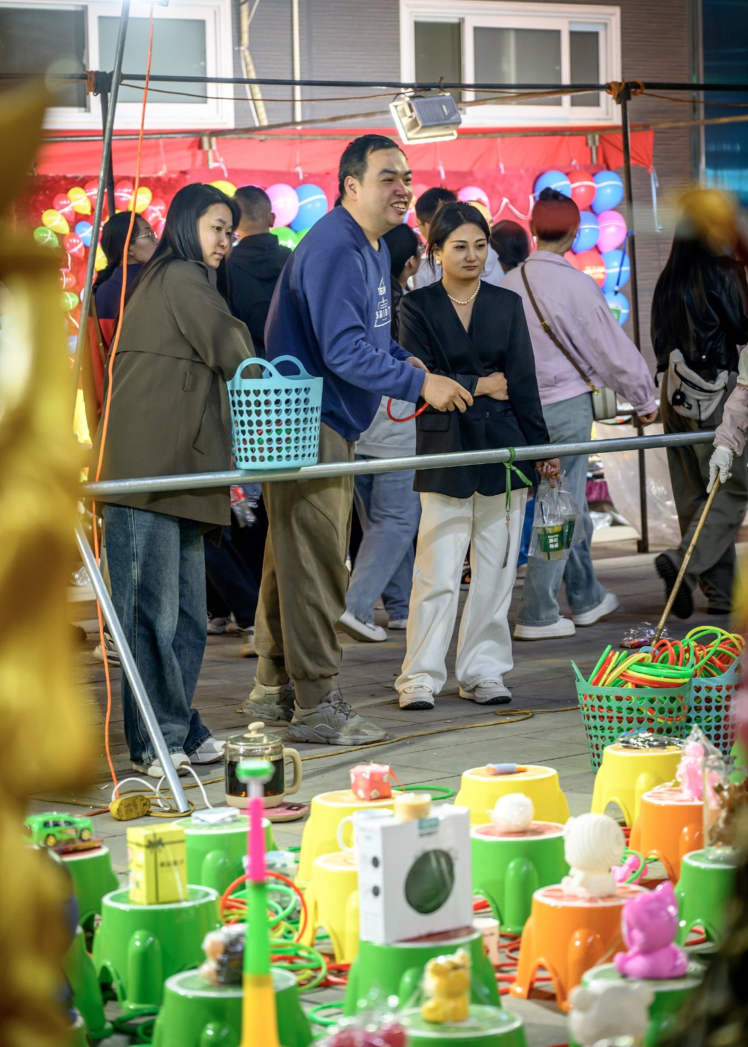 2024年4月19日，石家庄正定小商品夜市，游客们在玩摊位前的小游戏。