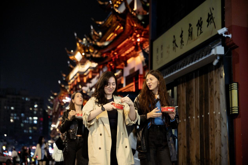 参加“免费上海半日游”的外国游客在城隍庙品尝小吃。 携程旅行供图