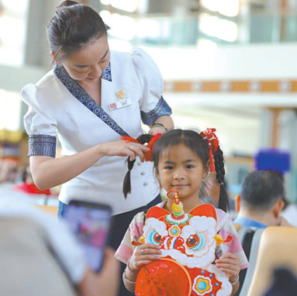2月16日，中老铁路老挝万象站，车站工作人员给泰国小旅客扎头发。杨永全 摄