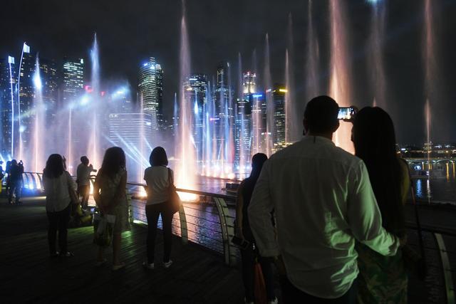 2022年4月28日，游客在新加坡滨海湾金沙观赏一场灯光喷泉秀。新华社发（邓智炜摄）