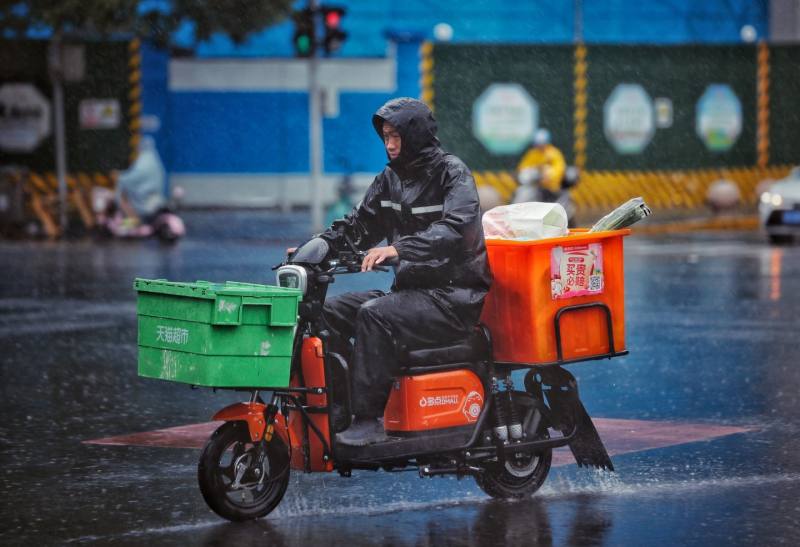 2023年7月22日，朝阳路，一位外卖小哥冒雨送货。 资料图片/新京报记者 薛珺 摄