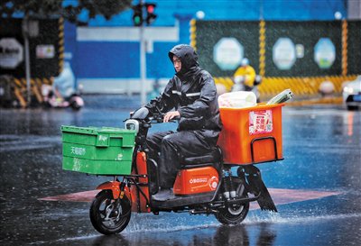 2023年7月22日，朝阳路，一位外卖小哥冒雨送货。资料图片/新京报记者 薛珺 摄
