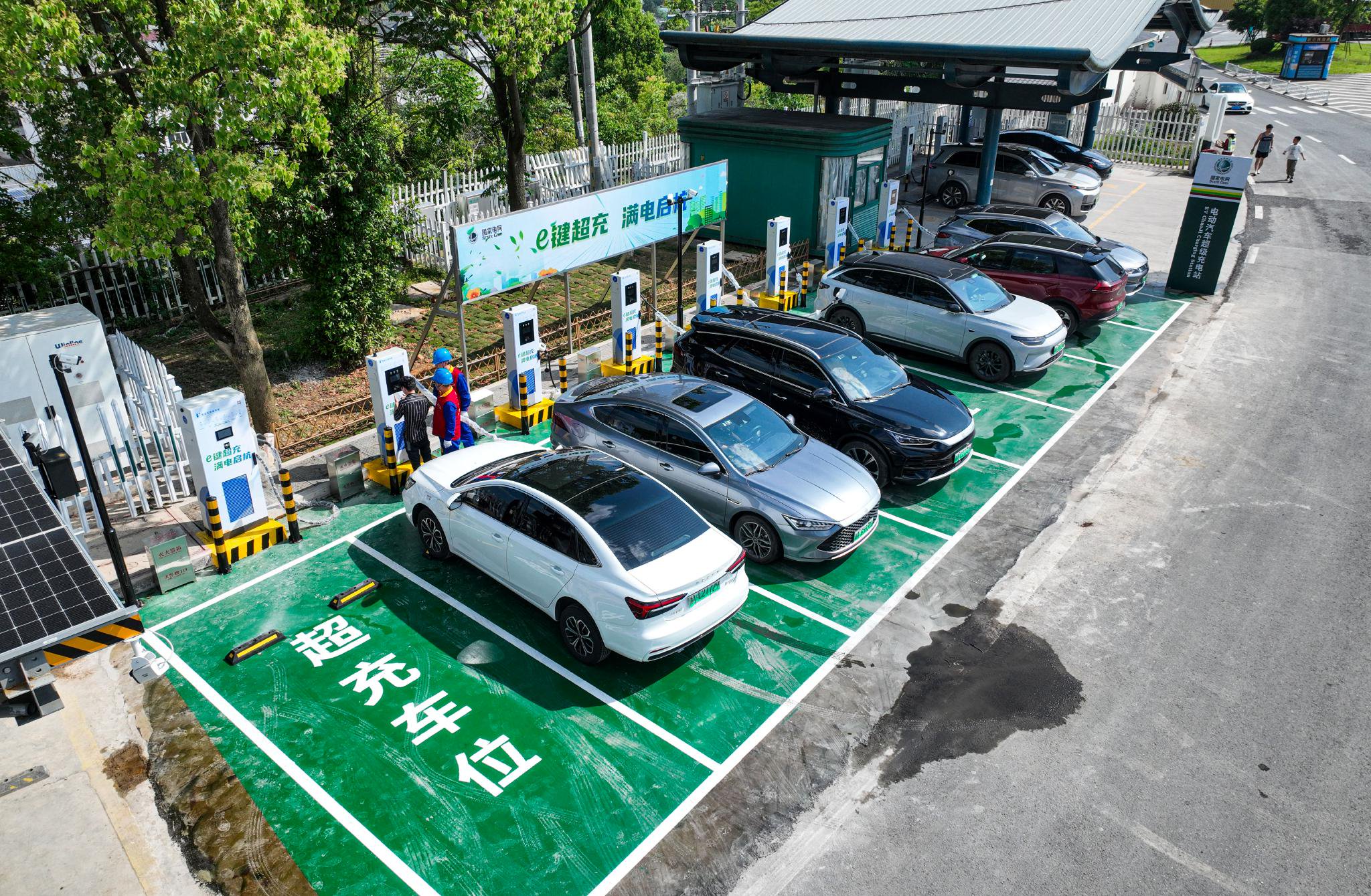 5月1日，国网杭州供电公司工作人员在杭新景高速服务区帮助新能源车主使用超快充电桩充电。唐衎 摄