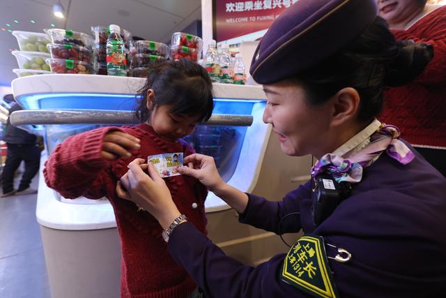 上海客运段列车乘务人员为儿童旅客贴上车厢号提示信息卡片。 姚佳 图