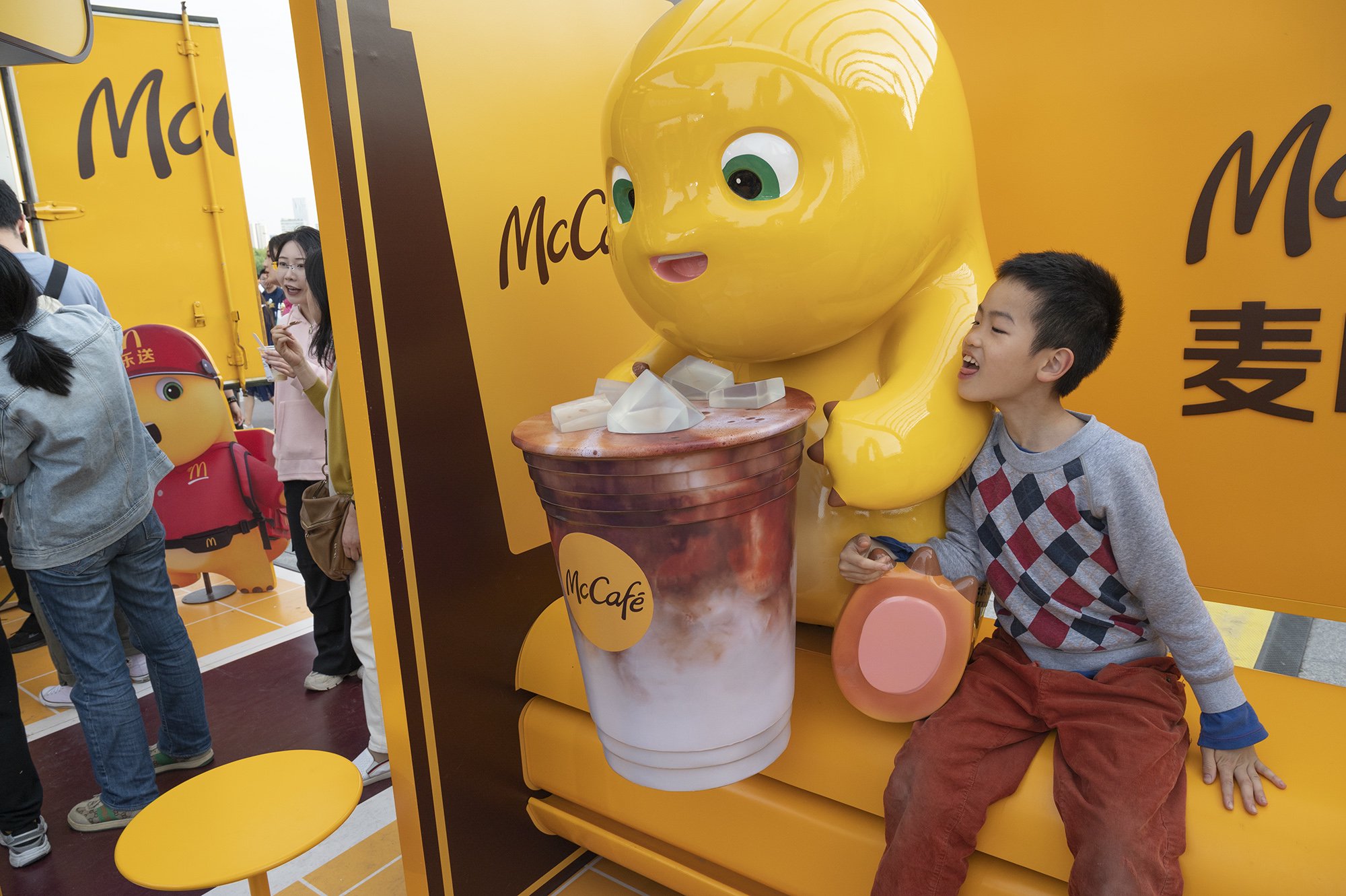 2024年5月1日，上海徐汇滨江。上海咖啡文化节上，一个男孩跑到奶龙前，假装舔一口咖啡杯里的咖啡。澎湃新闻记者 吴栋 图