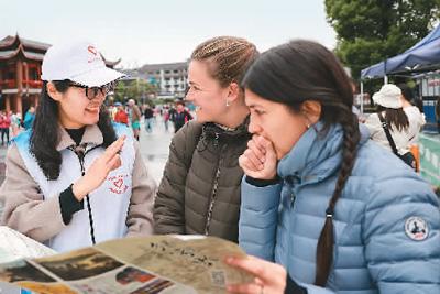 5月4日，湖南省张家界市武陵源区的青年志愿者为外国游客介绍景区游览线路。吴勇兵摄