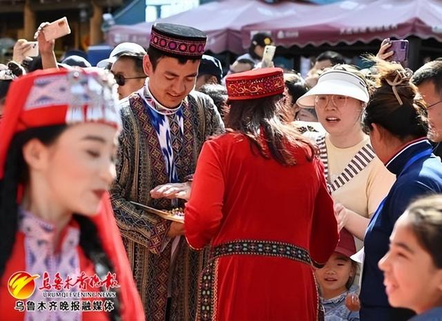 　　5月5日，在大巴扎步行街塔吉克族婚礼演艺现场，演员正在向游客分发喜糖分享幸福时刻。