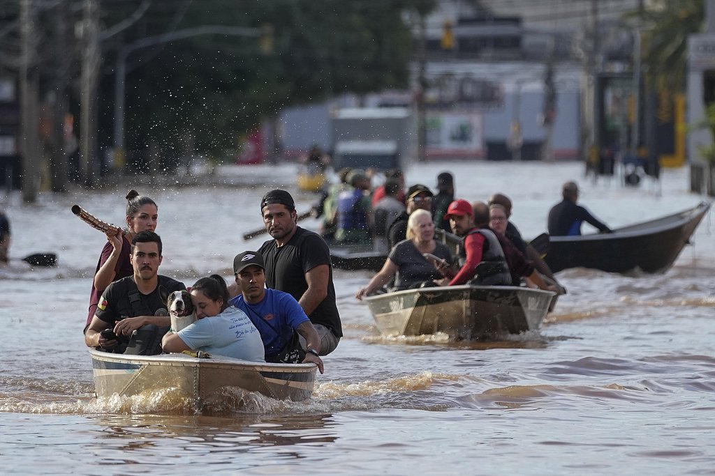 当地时间2024年5月7日，巴西阿雷格里港，志愿者帮助被暴雨淹没的地区的居民撤离。