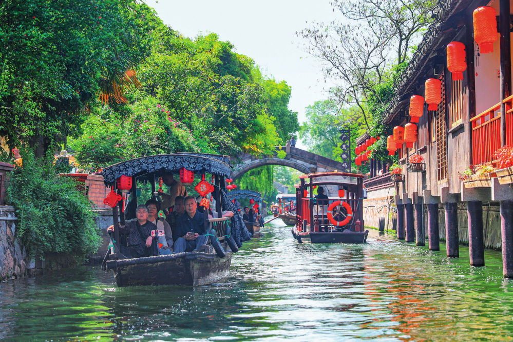 湖州市南浔古镇阳光明媚,游客乘坐摇橹船欣赏风景(2024年4月24日摄)