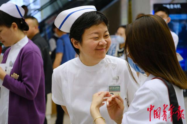 5月11日，北京协和医院西单院区门诊大厅，一名护士与清华大学学生艺术团的同学交流。田嘉硕/摄