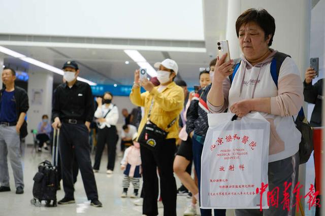5月11日，北京协和医院西单院区门诊大厅，前来就诊的患者拿起手机拍摄演出。田嘉硕/摄