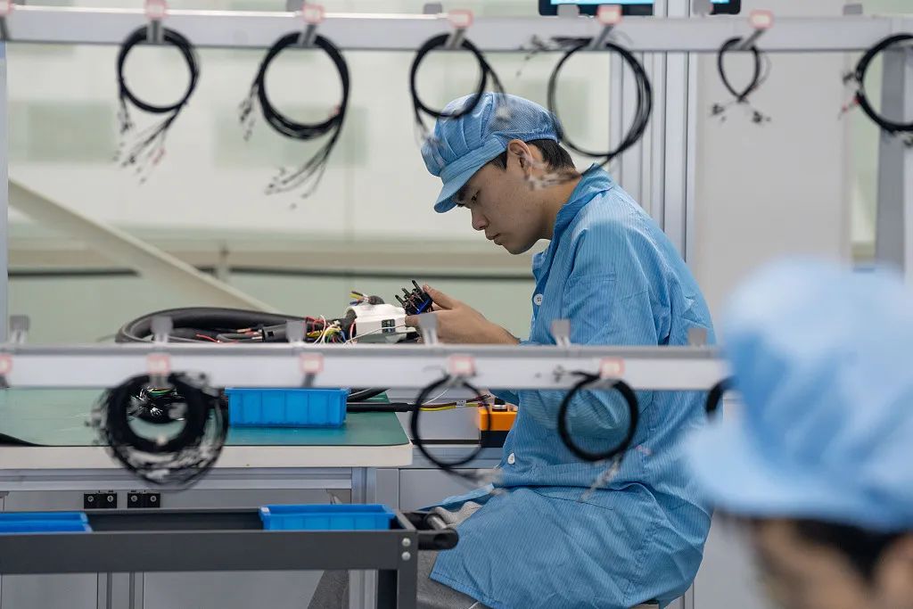 循环经济示范园内一车间内,技术人员们在梳理电动汽车充电桩插头线束
