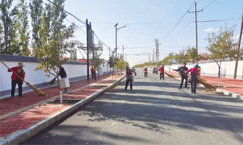 图为博乐市小营盘镇铁日木布拉格村村民清扫村内街道.