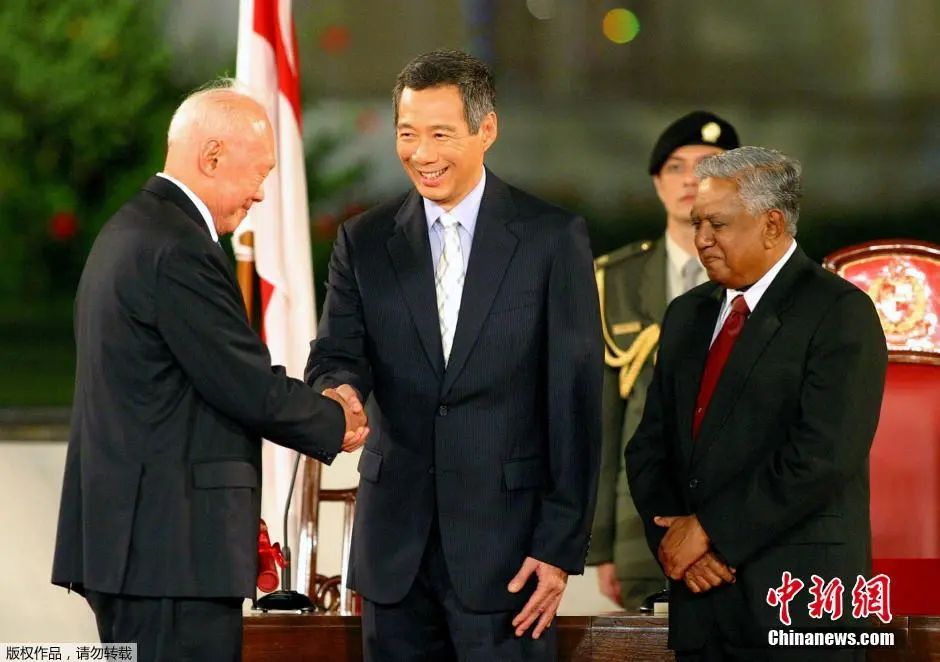 图为2004年李显龙宣誓就任新加坡总理后与自己的父亲李光耀握手。