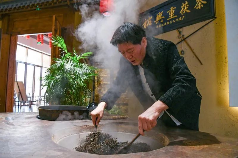 茯茶国家级非遗传承人罗荣利正在展示炒茶工艺