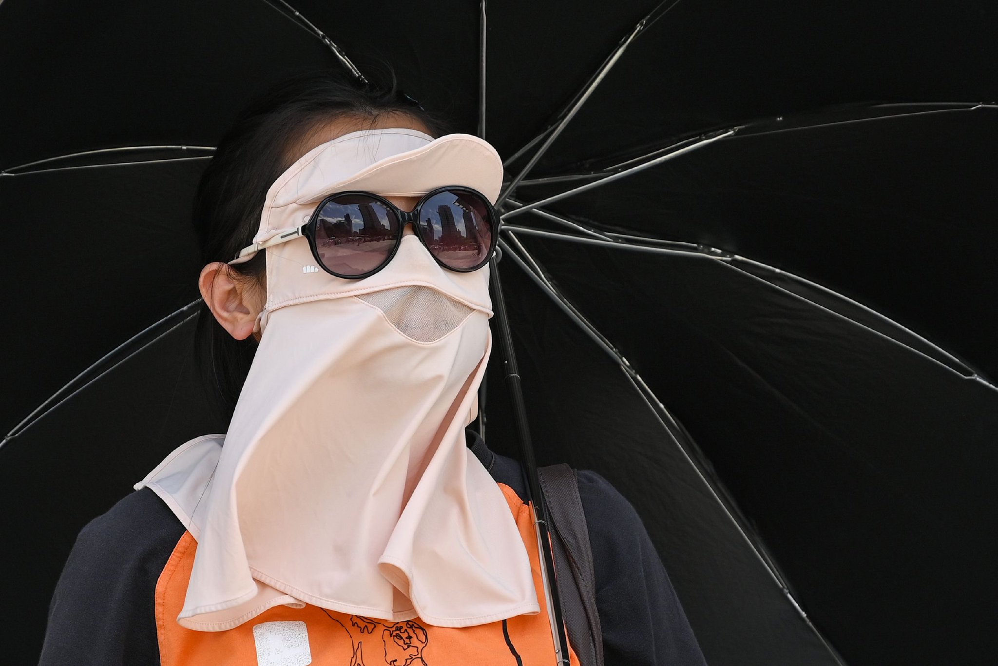 2024年5月17日,上海,行人戴着防晒面罩,撑着伞出行.