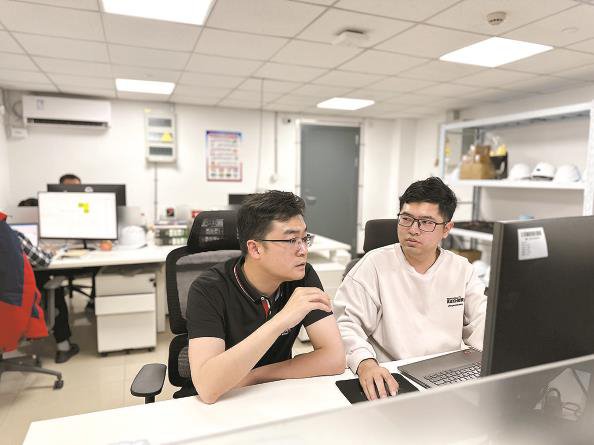 杨钊（左）和同事讨论技术难题 本报记者 杨欢 摄