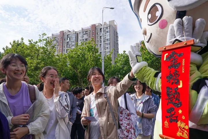 6月7日，在江苏省南京市建邺区中华中学考点，考生与送考人偶击掌。新华社记者 李博 摄