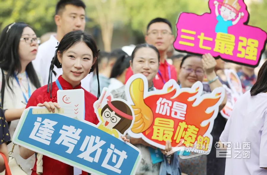 老师们身着旗袍、手持标语为考生们加油鼓劲。