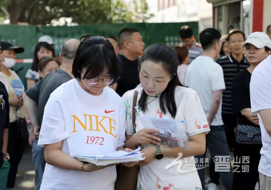 一对母女在考场外认真回顾重要知识点。