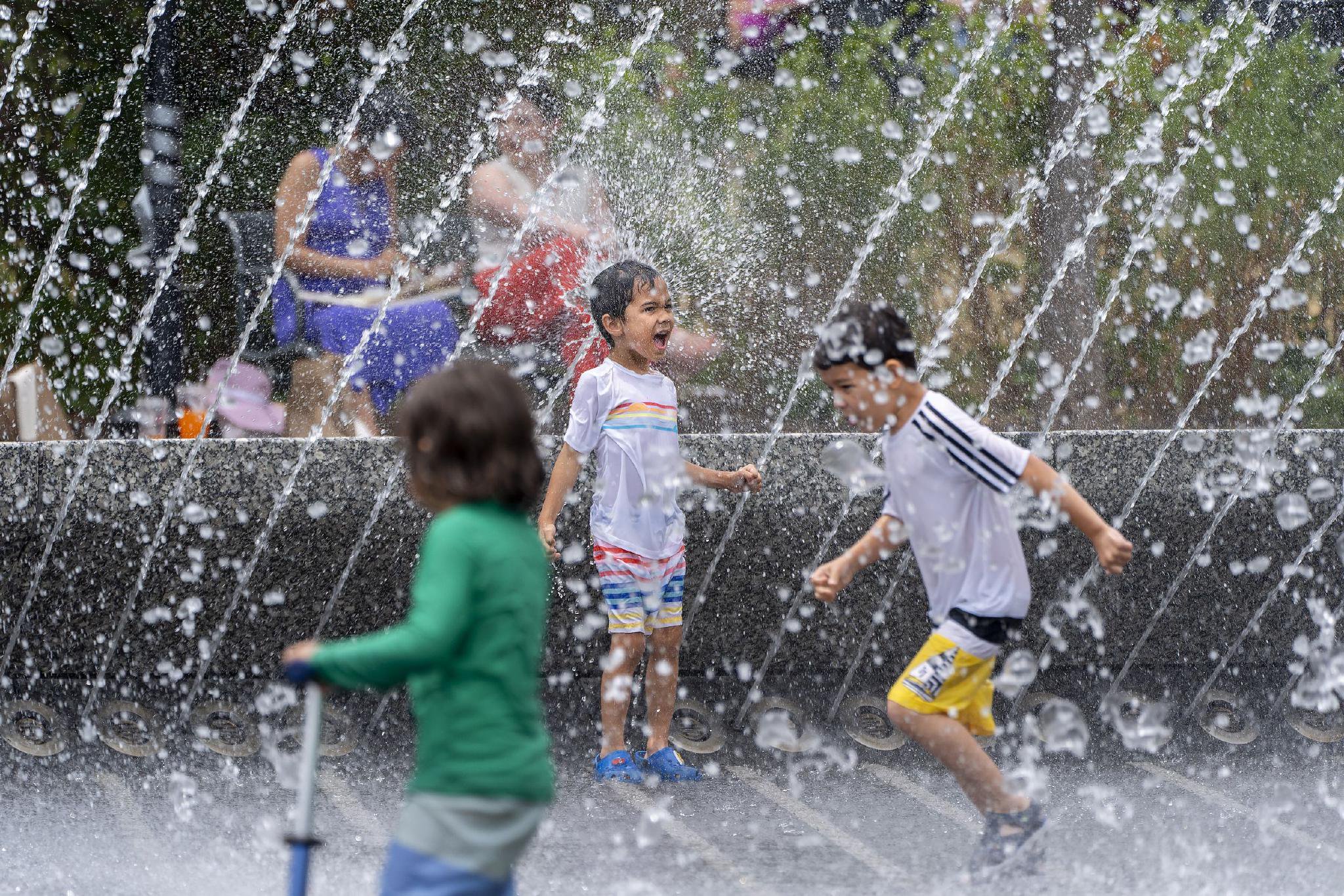 当地时间2024年6月23日，美国华盛顿特区，一群孩子在乔治城海滨公园的一处喷泉戏水降温。视觉中国 图