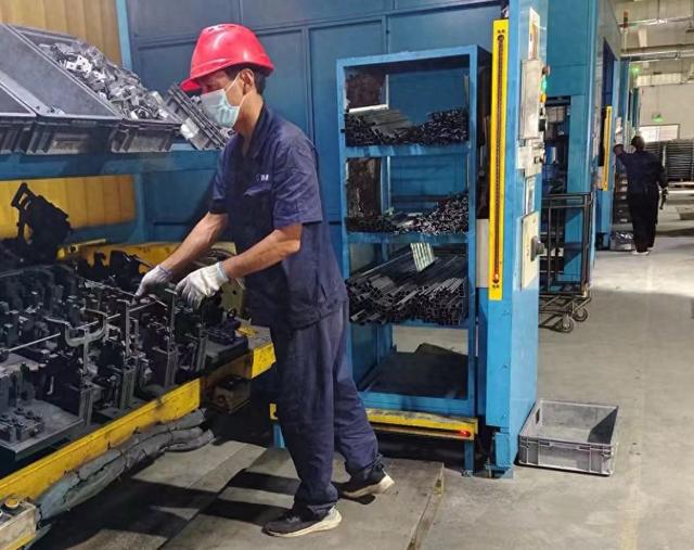 在鄠邑区新能源汽车电子产业基地，一位工人正在将零件放在自动焊接平台上。 人民网 吴德锋 摄